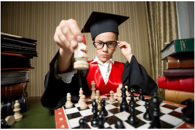 Boy playing chess in cap and gown